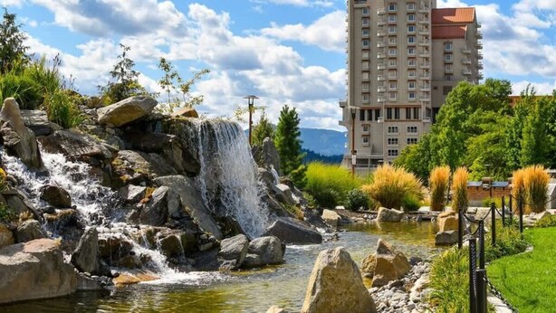A hotel with a large building, a waterfall, and a pond.