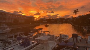 A marina with boats docked, a building with arched windows, and a sunset over the water. - 3 bedroom home with pool (Sandys)
