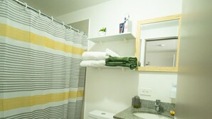 A bathroom with a striped shower curtain, a toilet, a sink with a towel, and a mirror. - Great Veiws 17th Floor IFreses! WiFI, A/C, Pool. (Curridabat)