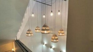 Una escalera de diseño moderno, con barandilla de vidrio e iluminación colgante con detalles de madera.