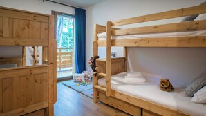 A bunk bed room with wooden furniture, a small play area with toys, and a view of the outdoors through a window. - Solly Nook - alpine holiday for 8, hot tub & close to action - OVO Network (Châtel)