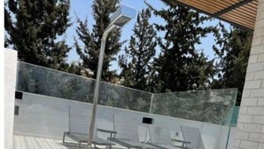 Un'area esterna riparata con pavimento decorato, ringhiera in metallo e una panca.