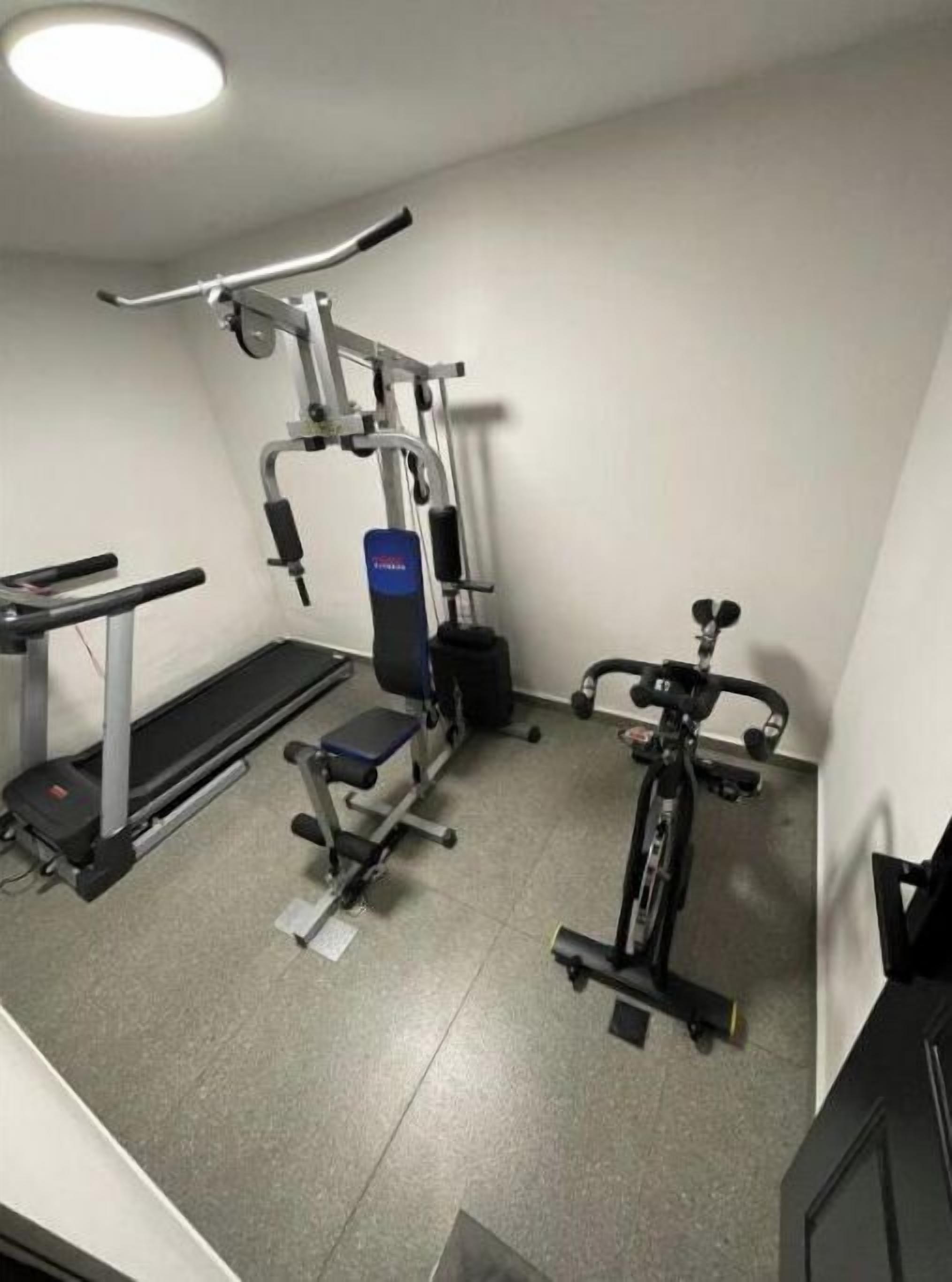 Ett gym med löpband, viktbänk och crosstrainer.