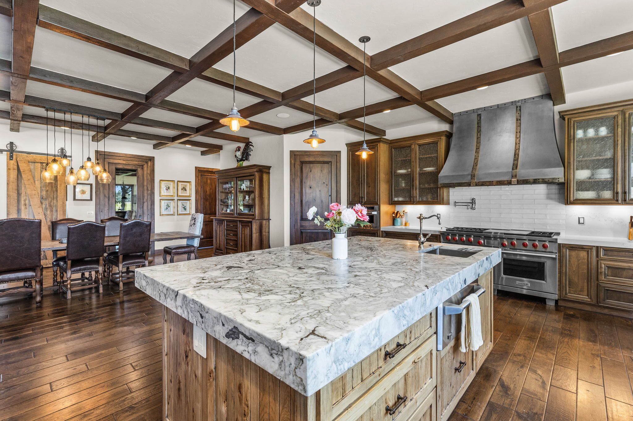 A spacious kitchen with a large island, wooden beams, and modern appliances.