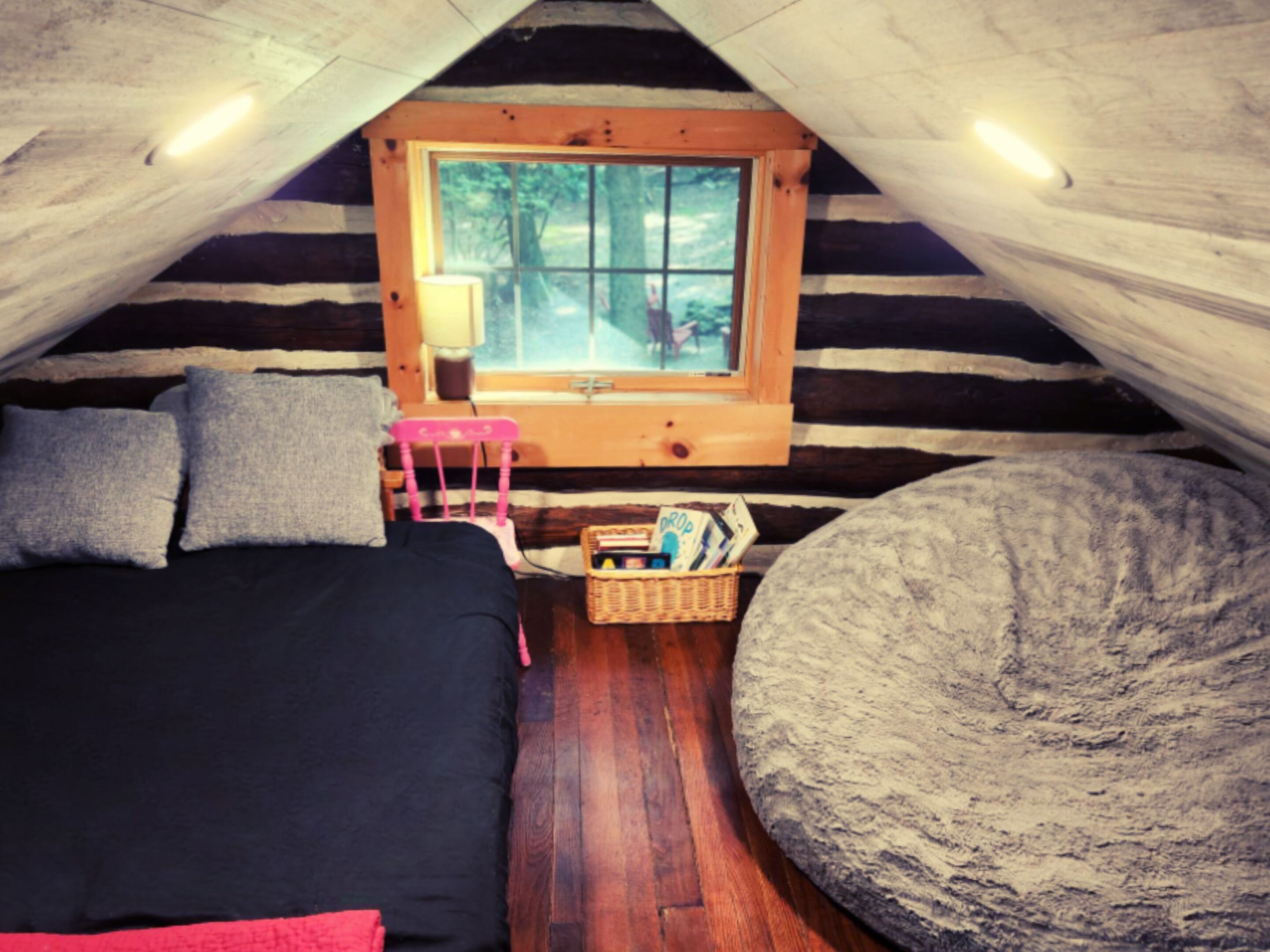 A cozy room with a bed, a chair, a window, and a basket of items.