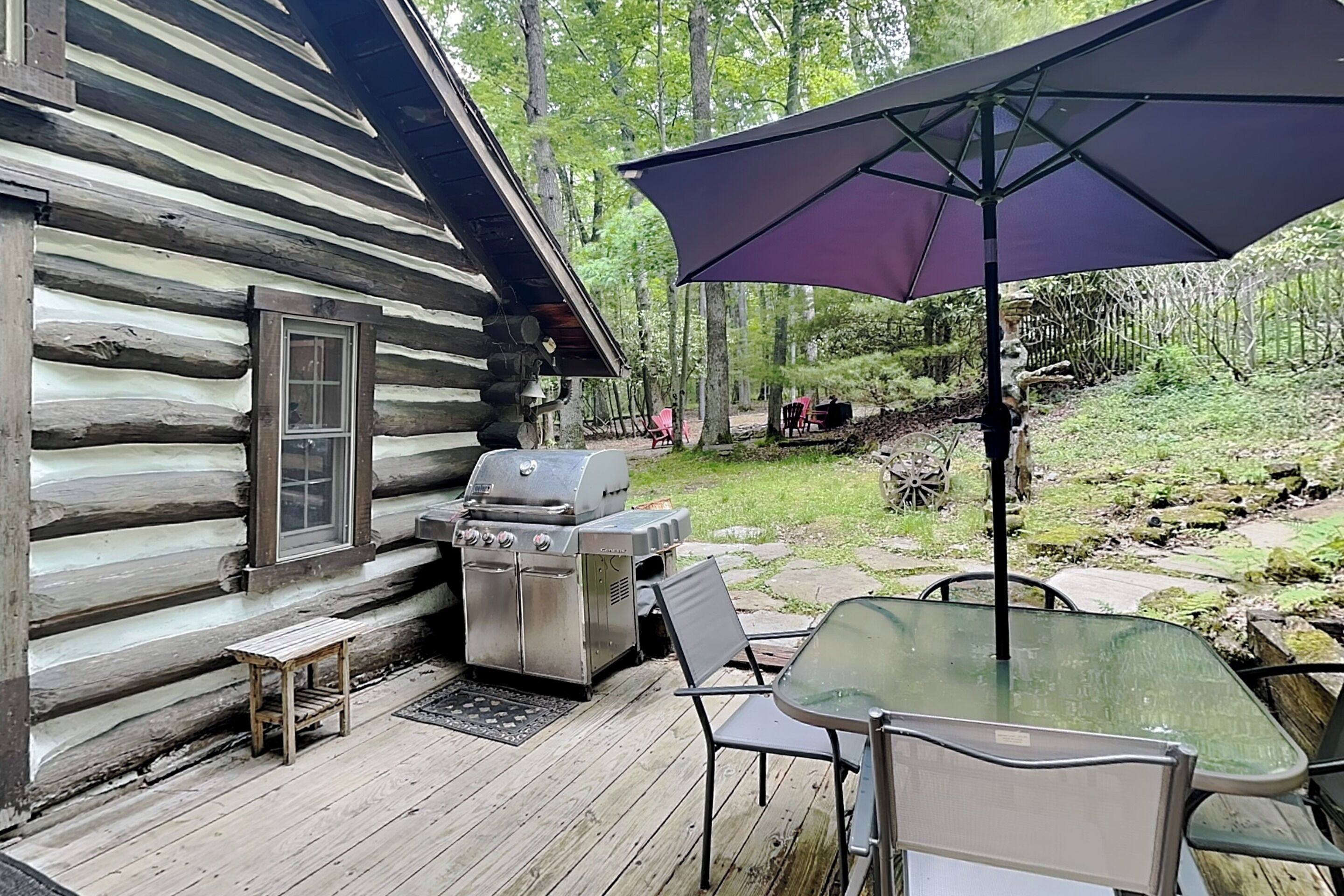 Une cabane en rondins avec un barbecue et un espace salon extérieur.