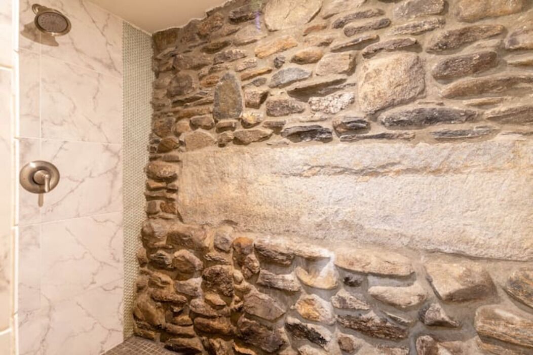 A bathroom with a stone wall and a shower area.