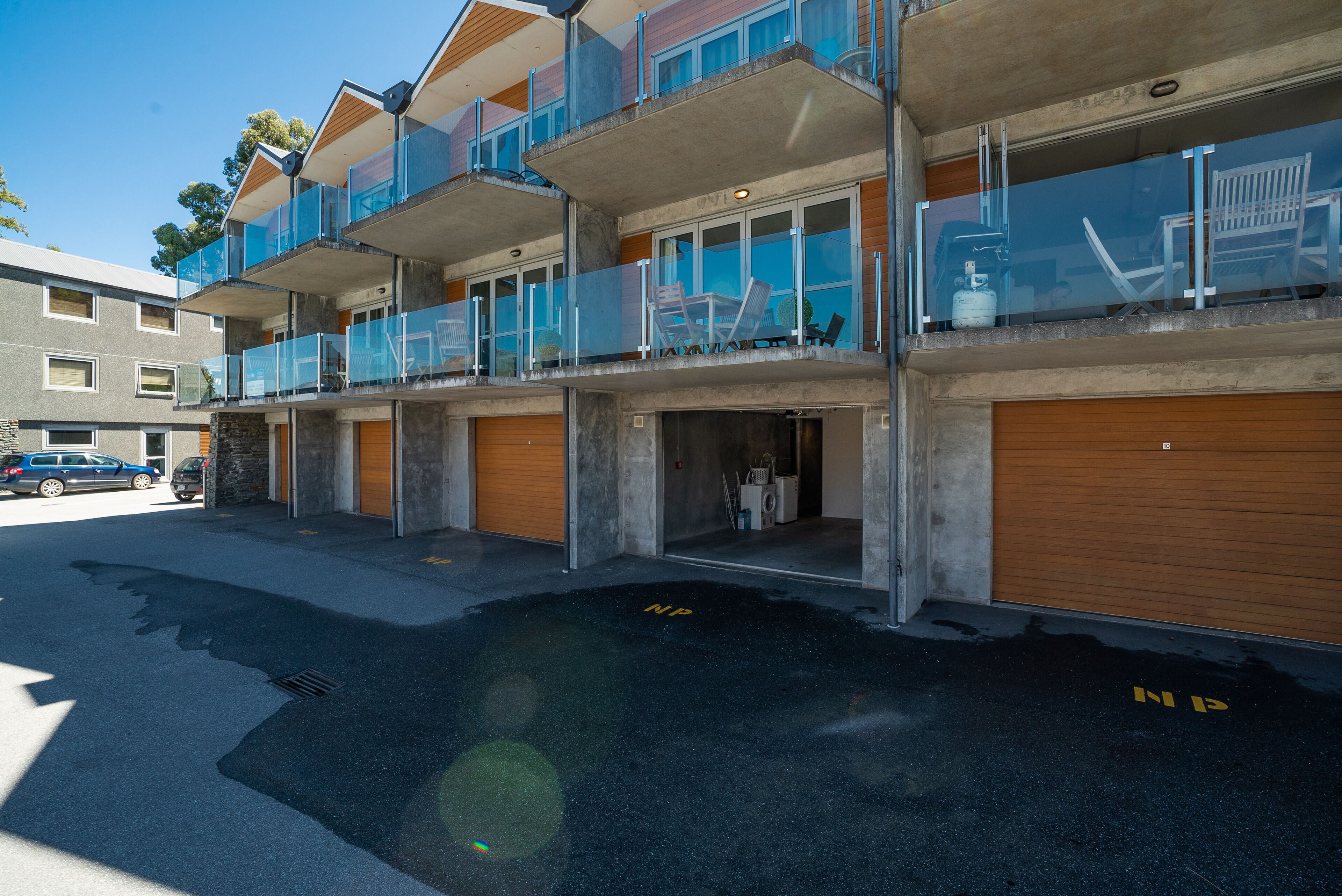 Un immeuble à plusieurs étages doté de balcons, de portes de garage et surplombant un ciel dégagé.