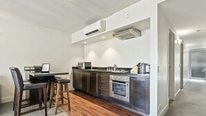 Een moderne keuken met donkere kastjes, een centraal eiland en een eethoek met barstoelen.