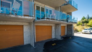 Een meerhoog gebouw met een balkon, een garagepoort en een parkeerplaats.