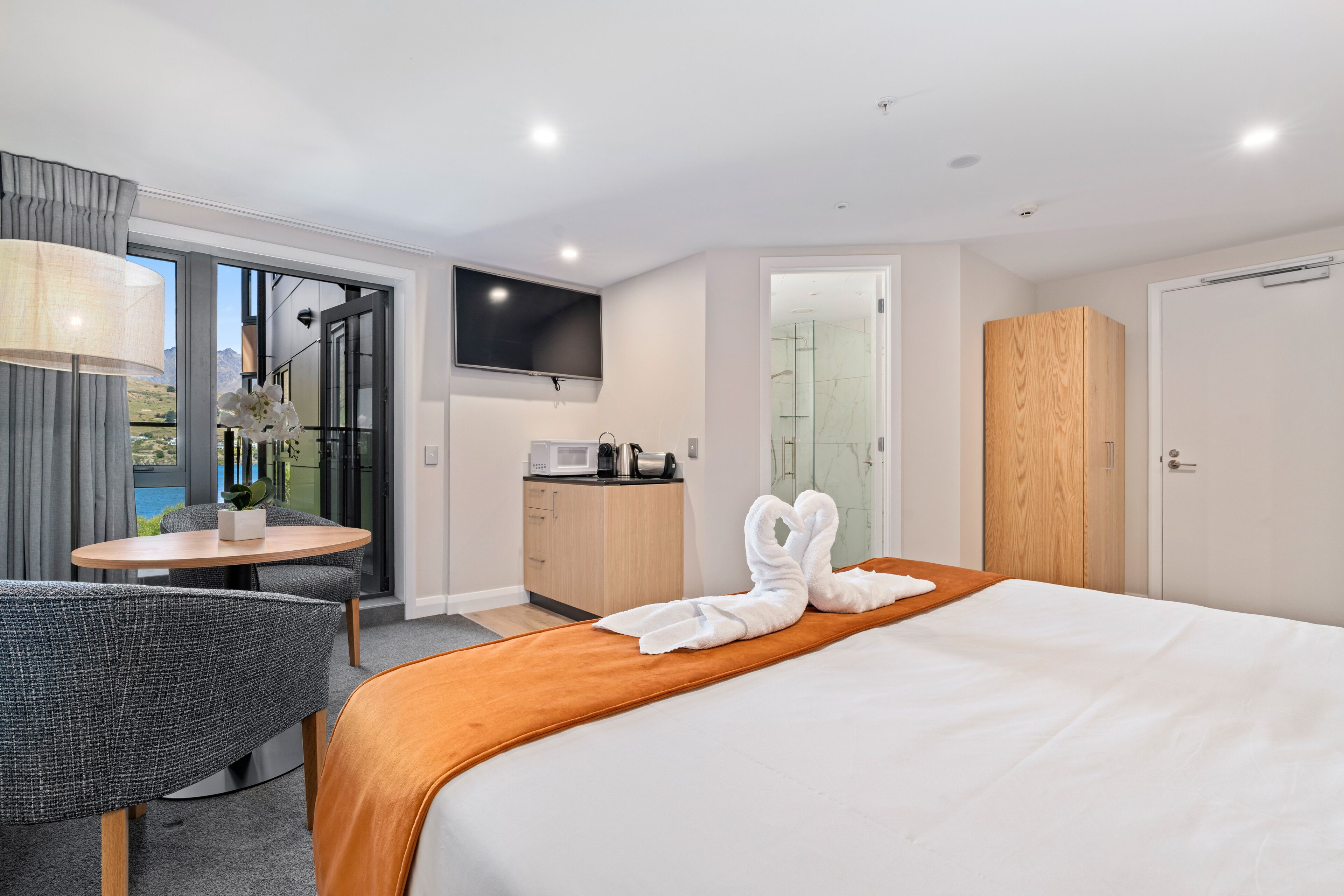 Ein Hotelzimmer mit Bett, Schreibtisch mit Stuhl, Fernseher, Dusche und Kleiderschrank.