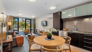 Une cuisine moderne avec des meubles de rangement aux couleurs sombres, un four encastré et une grande fenêtre.