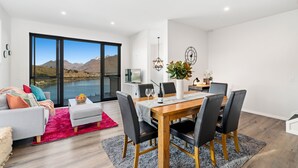 A modern living room with a dining area, large windows with a mountain view, and a cozy seating arrangement. - A LUCKIE CHARM - 3-BEDROOM TOWNHOUSE WITH SPECTACULAR VIEW (Queenstown Hill)