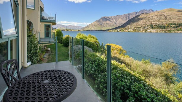 Uma casa moderna com varanda com vista para um lago e montanhas.