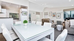 Uma sala de estar moderna com uma mesa de jantar de vidro, sofás brancos e um sofá bege.
