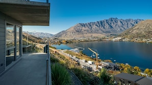 A modern building with a balcony overlooking a lake and mountains. - MODERN ALPINE LIVING SPECTACULAR VIEW (Queenstown)
