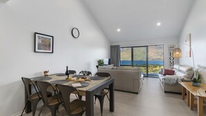 Un espace de vie moderne comprenant un coin repas, un canapé et une vue sur la mer.