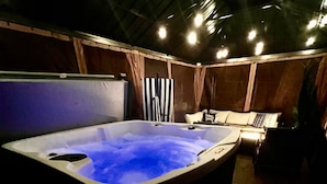 Een jacuzzi in een schemerige ruimte met houten wanden en een plafond.