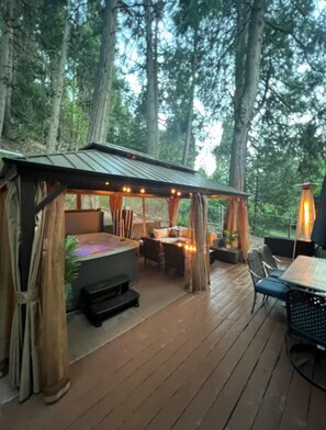 En utomhusveranda med ett tak över sittområdet, ett bord och en grill.