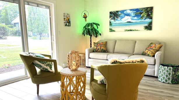 Ein Wohnzimmer mit einer Couch, zwei Sesseln, einem runden Tisch und einer Zimmerpflanze.