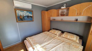 Une chambre à coucher comprenant un lit, une armoire, une étagère avec des objets décoratifs et un tableau au mur.