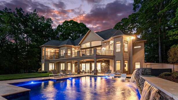 A two-story house with a swimming pool, outdoor seating, and a waterfall feature. - Sunset on Ballycastle w/Heated Pool & Optional Boat Rental (Mooresville)