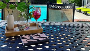 A patio with a table set for tea, a vase with flowers, and a view of a swimming pool. - Cheerful four bedroom house with charming view! (Santa Clarita)