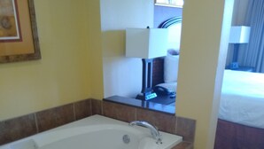 Une salle de bain avec une baignoire, un miroir et une fenêtre.