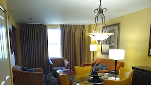 Une chambre d’hôtel comprenant un coin repas, un canapé, une chaise, une table et une lampe.