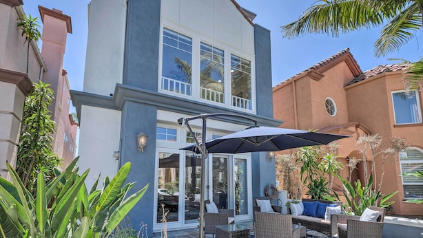 Une maison moderne dotée d’un patio aménagé avec du mobilier d’extérieur et un grand parasol.