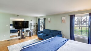 A bedroom with a bed, a blue sofa, a television, and a window with curtains.