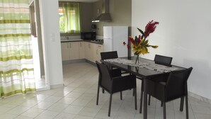 Un comedor con una mesa, sillas y un jarrón de flores.