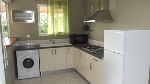 Una cocina compacta equipada con lavadora, estufa, microondas y refrigerador.