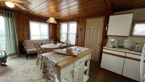 Una habitación acogedora de estilo cabaña con comedor, kitchenette y vistas al océano.