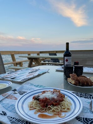 Una mesa preparada con platos de espagueti, una botella de vino y salsas.