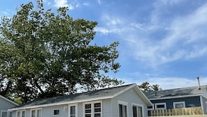 Una casa móvil con una terraza de madera y un árbol al fondo.
