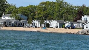 Un conjunto de cabañas frente a la playa, con arena y un muelle.