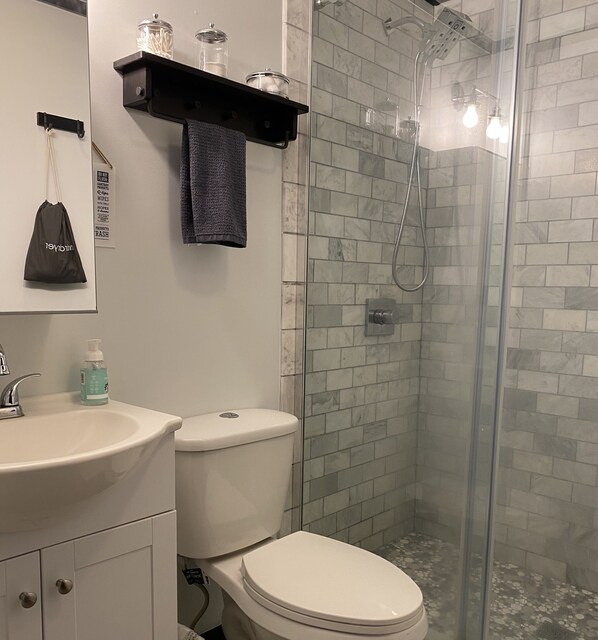 A bathroom with a white sink, a toilet, a glass shower enclosure, and a towel hanging on a rack. - Holly Forest Treehouse - Dogs Welcome! (Sapphire)