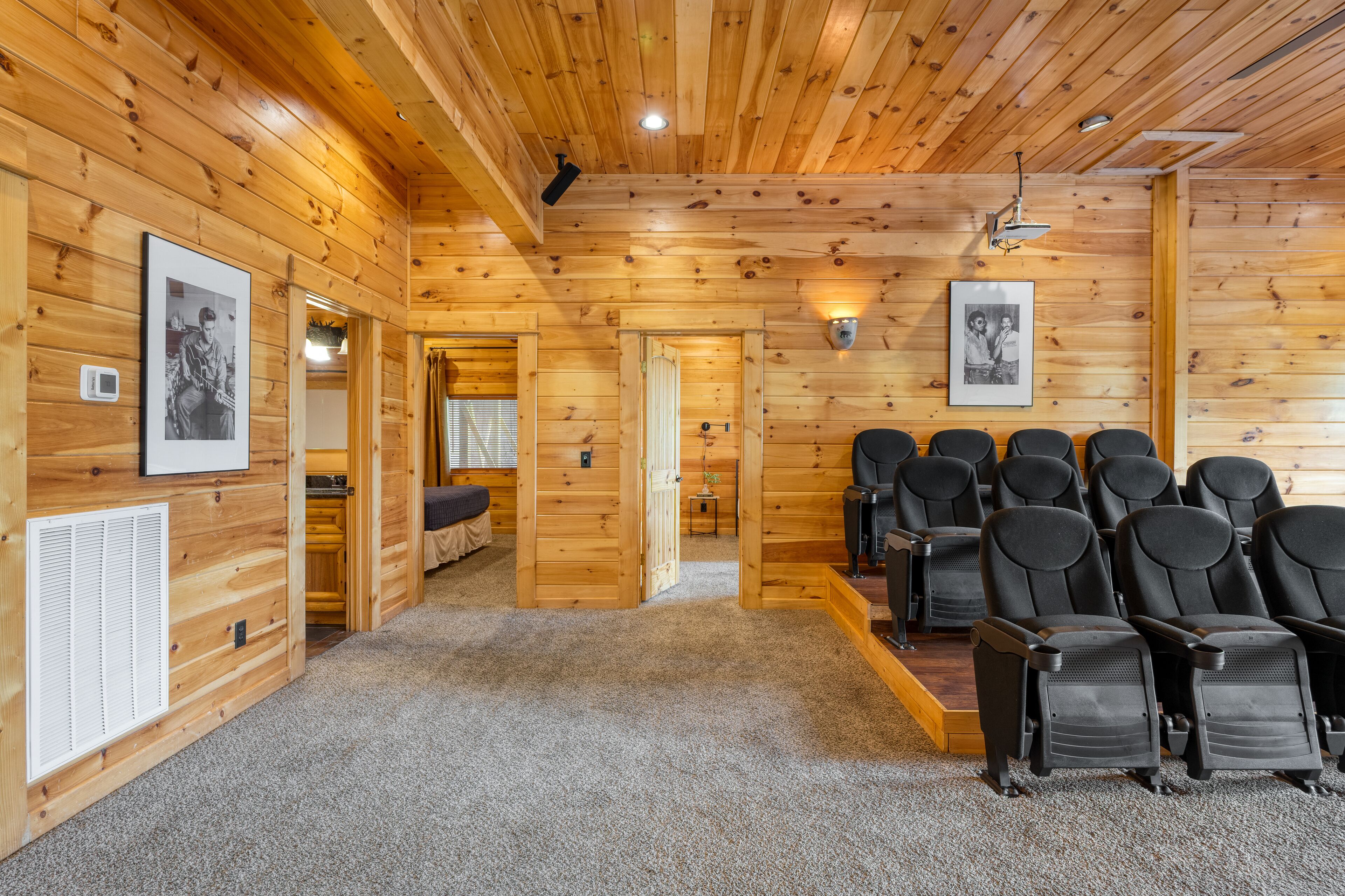 A wooden interior with a seating area, a small kitchenette, and a door leading to another room.