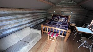 L’intérieur d’un chalet accueillant, avec un lit en bois, un canapé et une petite table.