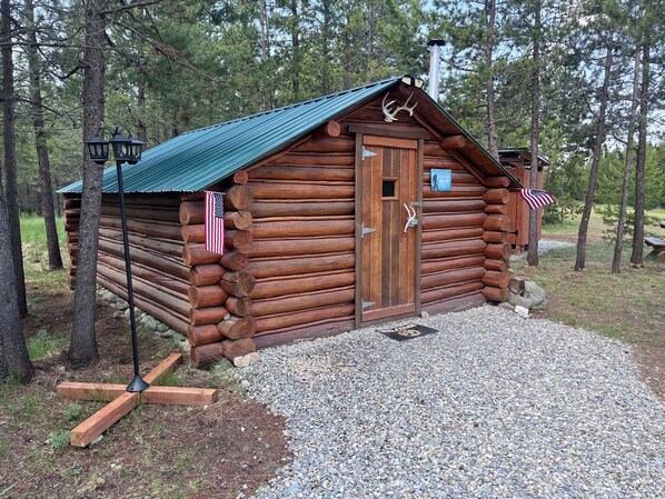 A wooden cabin with a green roof, surrounded by trees. - Retreat to our cozy cabin nestled in a private hideaway.
Solar lights & shower (Marion)