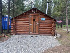 A rustic log cabin with a wooden door, an American flag, and a sign indicating a 'Free Fire Range' nearby. - Retreat to our cozy cabin nestled in a private hideaway.
Solar lights & shower (Marion)