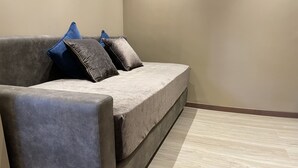 Un sofá gris con suelo de madera clara y pared lisa.