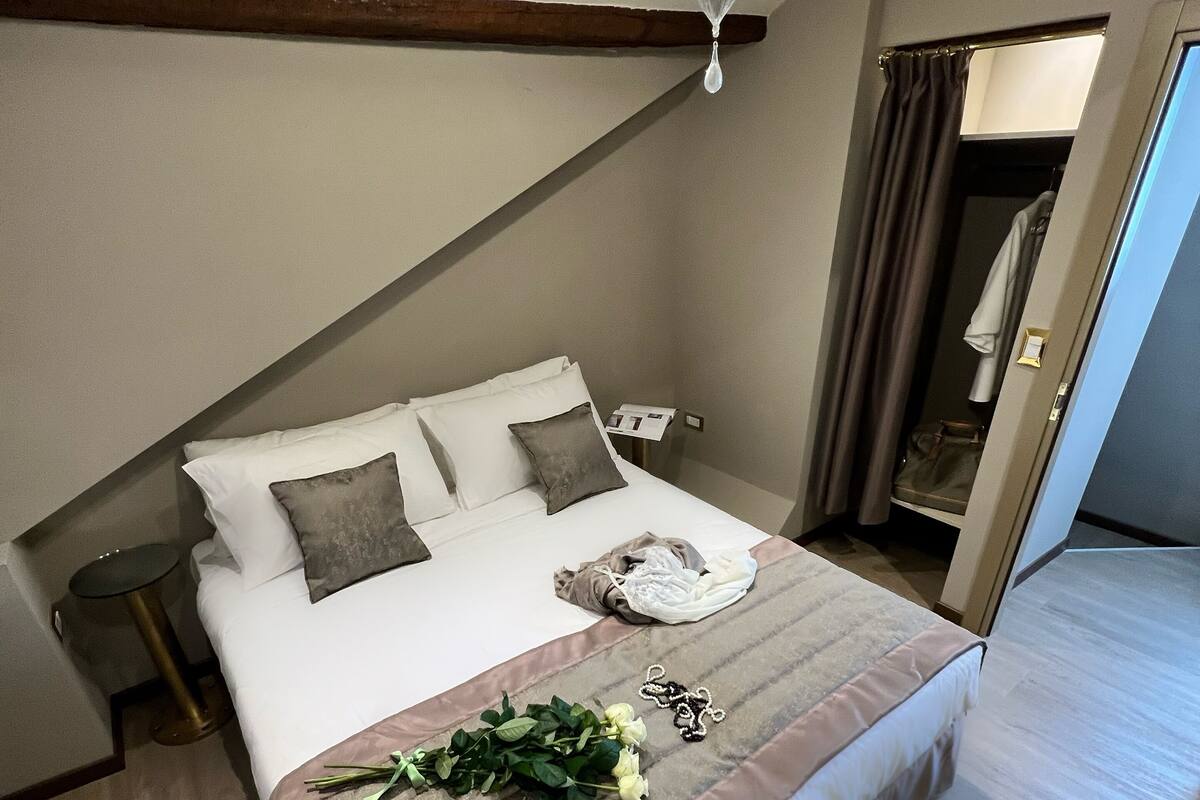 A bedroom with a bed, bedside tables, a chandelier, and a mirror.