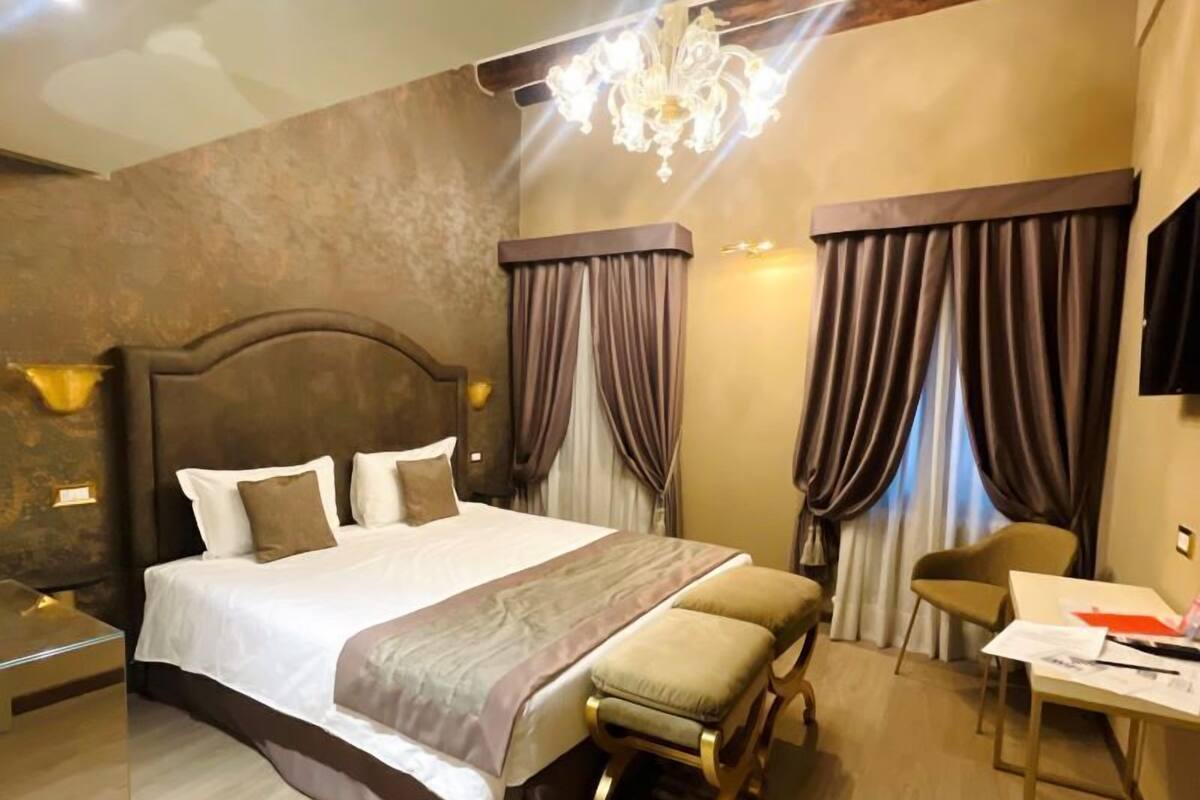 A modern hotel room with a large bed, a desk, and a chair.