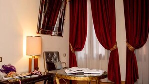 Una habitación con un sillón de cuero, una mesa de vidrio, una lámpara y cortinas rojas.