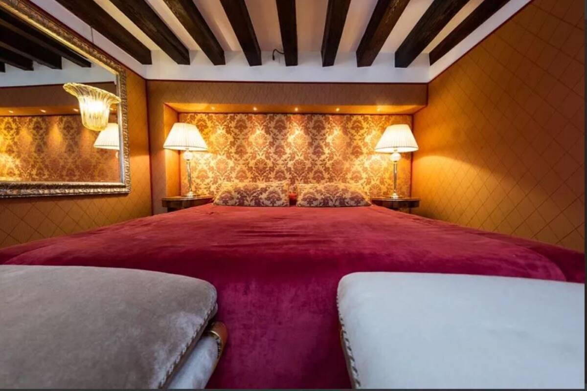 A hotel room with a large bed, two bedside lamps, a mirror, and a patterned wallpaper.