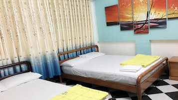 A room with two single beds, a wooden headboard, a checkered floor, and a curtain with a floral pattern.