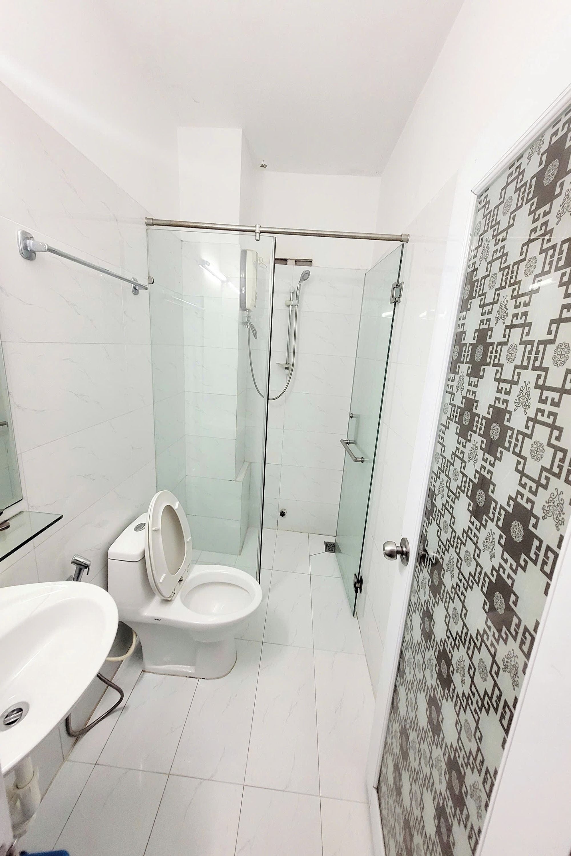 A modern bathroom with a glass-enclosed shower, a toilet, and a sink.