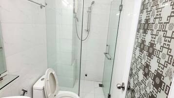 A modern bathroom with a glass-enclosed shower, a toilet, and a sink.